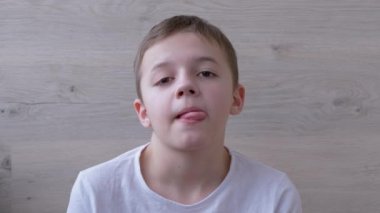 Dolgun dudaklı, uzun kirpikli, suratını ekşiten, dilini uzatan çocuk. Mizah. 4K