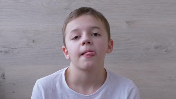 Αγόρι με πλήρη χείλη, μακριά βλεφαρίδες κάνει γκριμάτσες, ξεχωρίζει γλώσσα. Χιούμορ. 4K — Αρχείο Βίντεο
