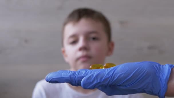 Der Arzt, ein Kinderarzt mit Latexnitrilhandschuhen, verabreicht dem Kind zwei Pillen. 4K — Stockvideo