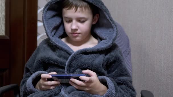 ( 영어 ) Boy in a Grey bathrobe Sits in Chair Playing Mobile Game on Smart Phone at Home — 비디오