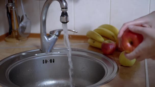 Mujer enciende un grifo, lava maduro, manzana roja en el fregadero, apaga el agua. 180 fps — Vídeo de stock