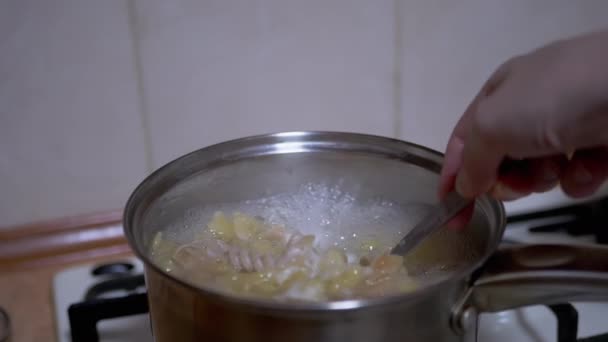 女性の手はスパゲッティを混合しています,スプーンを沸かすの鍋のパスタ — ストック動画
