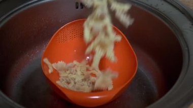 Turuncu Color Colander 'da pişirilmiş makarnadan kadın su emiyor. Yavaş çekim