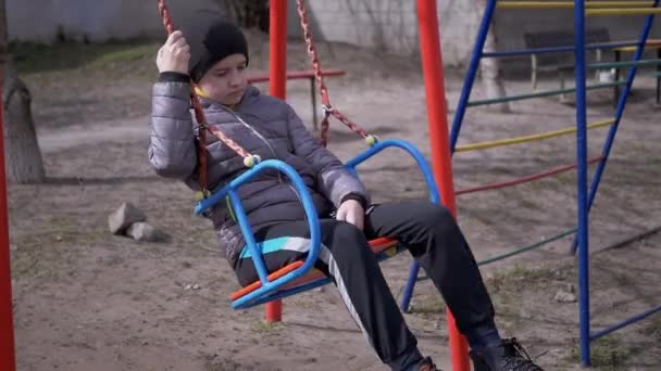 Lonely, Sad Child Swinging on a Swing in the Yard Without Friends. Slow-motion — Stock Video