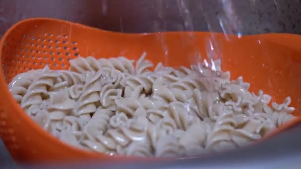 Corriente de agua vierte sobre la pasta hervida. Burbujas, salpicaduras. 4K. De cerca. — Vídeo de stock