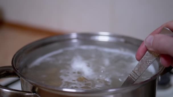 Kvinnlig hand en sked rör Pasta, Macaroni i en aucept av kokande vatten — Stockvideo