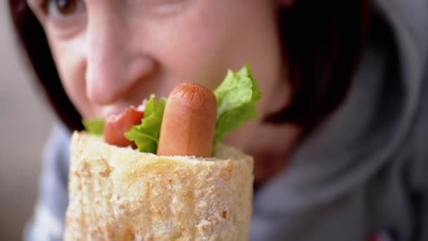 Hladová žena jí chuť šťavnatý americký hot dog s klobásami v jídelně — Stock video