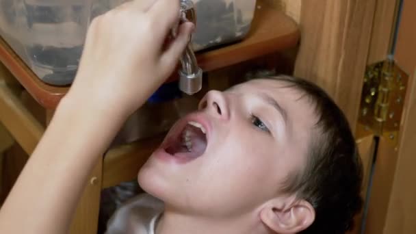 Yakışıklı çocuk mutfaktaki bir soğutucudan taze temiz su içiyor. — Stok video