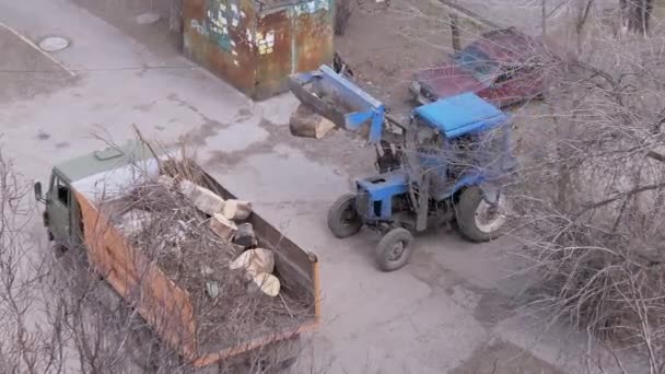 Tracteur avec grand seau, charge des arbres coupés, décharges dans un camion à benne basculante, camion. Zoom — Video
