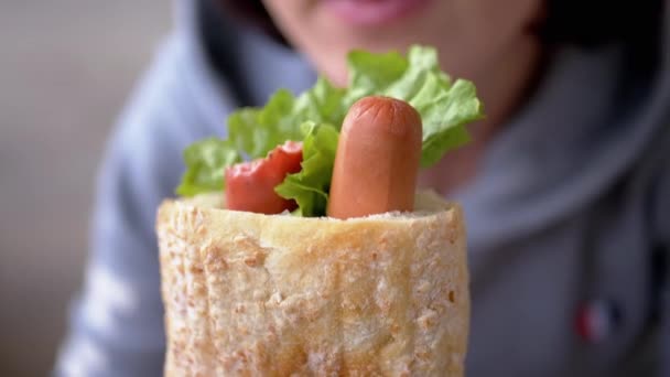 Kobieta gospodarstwa w rękach ugryziony soczysty amerykański hot dog z kiełbaskami w restauracji — Wideo stockowe