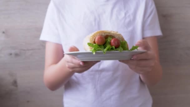 Armas infantiles trae plato jugoso American Hot Dog con salchichas y hojas de lechuga — Vídeos de Stock