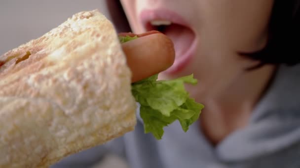 Πεινασμένη γυναίκα τρώει ορεκτικό ζουμερό αμερικανικό χοτ ντογκ με λουκάνικα σε ένα εστιατόριο — Αρχείο Βίντεο