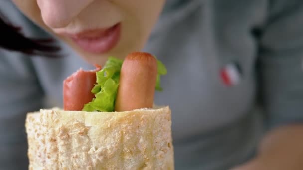 Mulher com fome come suculento suculento cachorro quente americano com salsichas em um restaurante — Vídeo de Stock