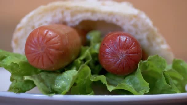 Νόστιμο, φρέσκο, ζουμερό αμερικάνικο χοτ ντογκ με δύο λουκάνικα, φύλλα μαρούλι. 4K — Αρχείο Βίντεο
