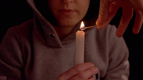 Kobieta trzyma świecę w rękach, mężczyzna podpala ją w ciemnym pokoju. 4K — Wideo stockowe