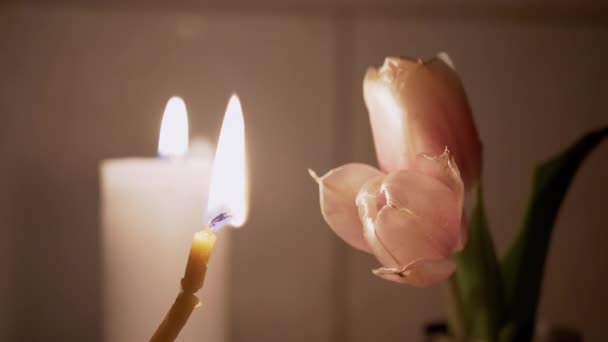 Cera e velas da igreja queimam com uma chama contra um fundo de flores desbotadas — Vídeo de Stock
