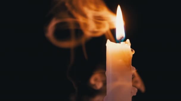 Vela, con cera de goteo, quema en una nube de humo sobre fondo negro — Vídeo de stock