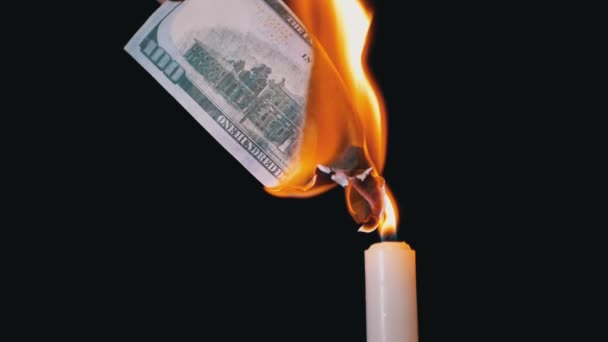 Billete de 100 dólares ardiendo sobre una llama de vela en un fondo negro — Vídeo de stock