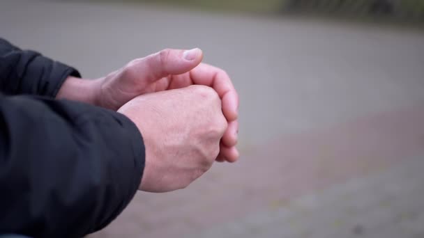 Seated Male Rubs Warm Hands Outdoors in the Park. Moment of Expectation, Anxiety — Stock Video