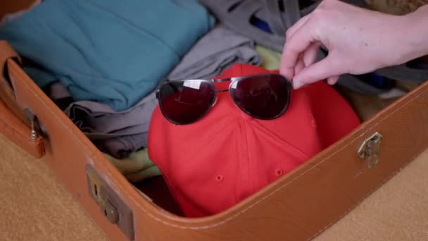 Mãos femininas enchendo uma mala com roupas de verão, uma máscara, óculos. 4K — Vídeo de Stock