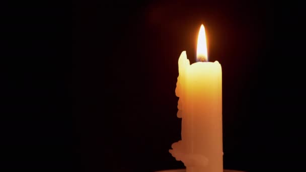 Желтая парафиновая свеча горит спокойным, ровным, огненным пламенем на черном фоне — стоковое видео