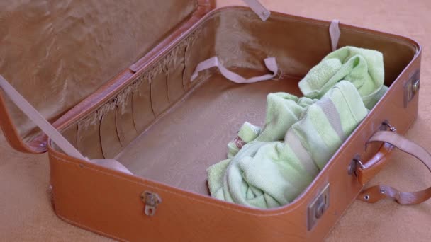 Otwarta stara brązowa walizka jest wypełniona rzeczami do podróży. Powiększ. Zamknij się. — Wideo stockowe
