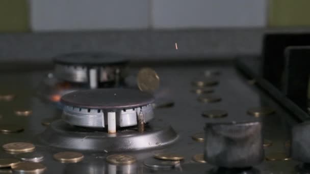 Монеты падают на газовую горелку, которая светится голубым пламенем на кухне — стоковое видео