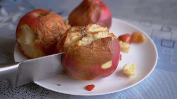 Kvinnlig hand skär ett ruttet äpple på en tallrik med en kniv. Bortskämda, mögliga frukter — Stockvideo