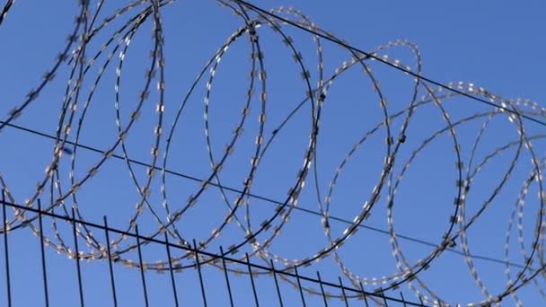 Fil barbelé suspendu à la frontière de la clôture de fer contre le ciel bleu. 4K — Video