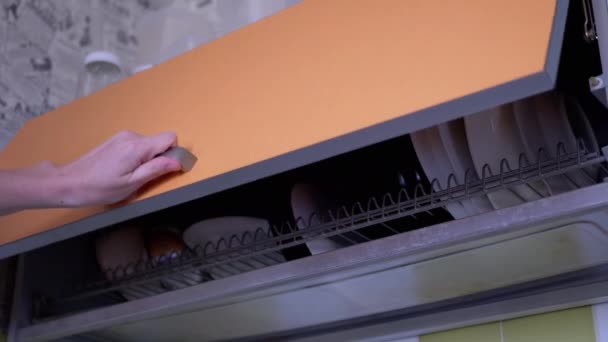 Γυναίκα ανοίγει την πόρτα του Cupboard με Dish Στραγγιστήρι και βάζει πλενόμενο πιάτο. 4K — Αρχείο Βίντεο