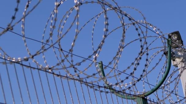 Fil barbelé suspendu à la frontière de la clôture de fer contre le ciel bleu. Zoom — Video