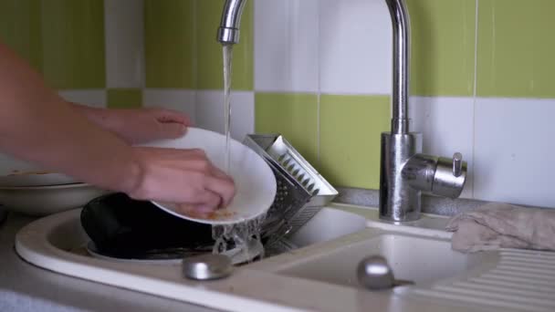 여성 손으로 스펀지를 사용하여 흐르는 물 속에서 부엌 싱크대에서 더러운 음식을 씻는다 — 비디오