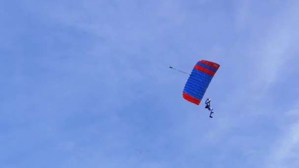 Spadochroniarz leci na paralotni w Błękitnym Niebie i ląduje na Zielonej Trawie. 4K. — Wideo stockowe