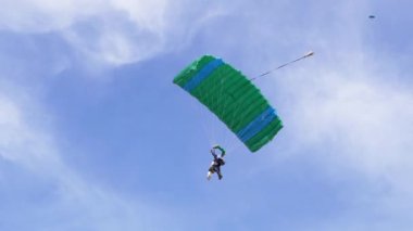 Paraşütçü Mavi Gök 'te Paraglider Üzerinde Uçuyor ve Yeşil Çimen' e İniyor. 4K