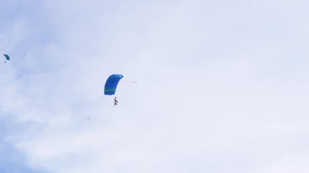 Los paracaidistas vuelan en un parapente contra el fondo del cielo azul con nubes. 4K — Vídeo de stock