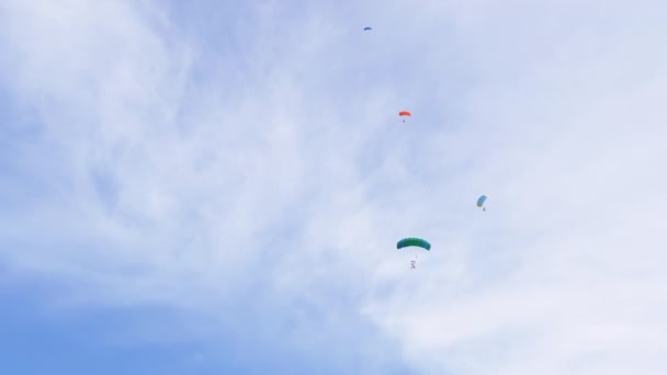 Los paracaidistas vuelan en un parapente contra el fondo del cielo azul con nubes. 4K — Vídeo de stock
