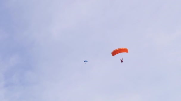 Parašutisté létat na padáku na pozadí modrého nebe s mraky. 4K — Stock video