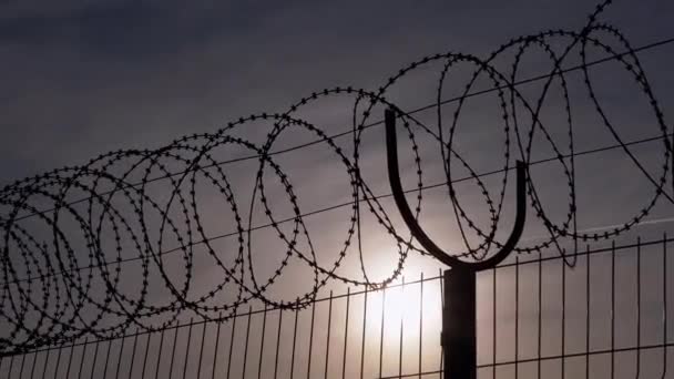 2016 년 1 월 9 일에 확인 함 . Barbed Wire Hangs on Border of a Iron Fence Against the Backdrop of Sunset. 4K — 비디오