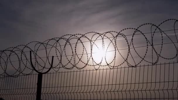 Barbed Wire Hangs on Border of a Iron Fence Against the Backdrop of Sunset. 4K — Stock Video