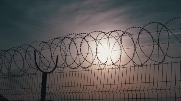 Barbed Wire Hangs on Border of a Iron Fence Against the Backdrop of Sunset. 4K — Stock Video