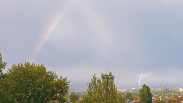 Erscheinen eines fantastischen hellen Regenbogens am Horizont durch graue Wolken am Himmel. 4K — Stockvideo