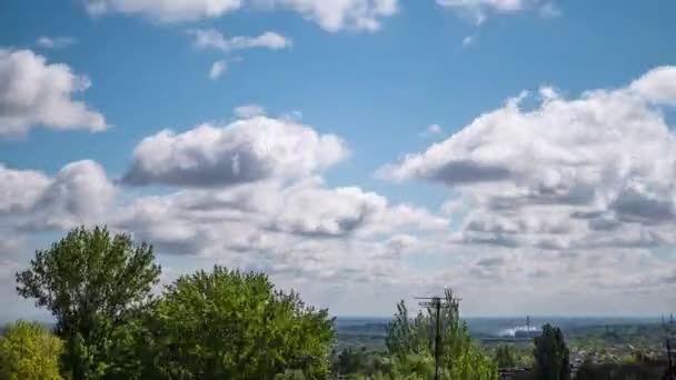 Nubes que se mueven rápidamente sobre las copas de árboles verdes, techos de casas, una fábrica. 4K — Vídeo de stock