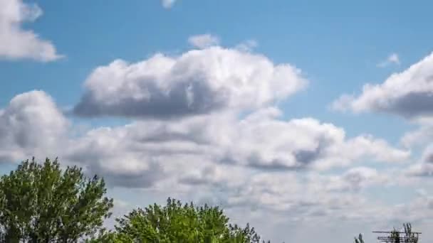 Nubes que se mueven rápidamente sobre las copas de árboles verdes, techos de casas, una fábrica. Zoom: — Vídeo de stock