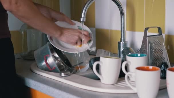 Mãos masculinas lava placa suja com uma esponja na pia da cozinha sob água corrente — Vídeo de Stock
