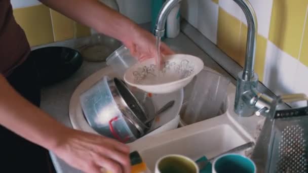 Männliche Hände waschen schmutzigen Teller mit Schwamm in Küchenspüle unter fließendem Wasser — Stockvideo