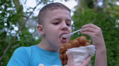 Çocuk Bench 'te oturur, Waffle kupasında kremalı dondurma yer, caddedeki parkta.