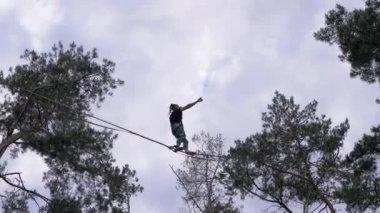 Cesur İp cambazı Çam Ormanında Sigortası Olan İp Üstünde Riskli Dublörler Gösteriyor