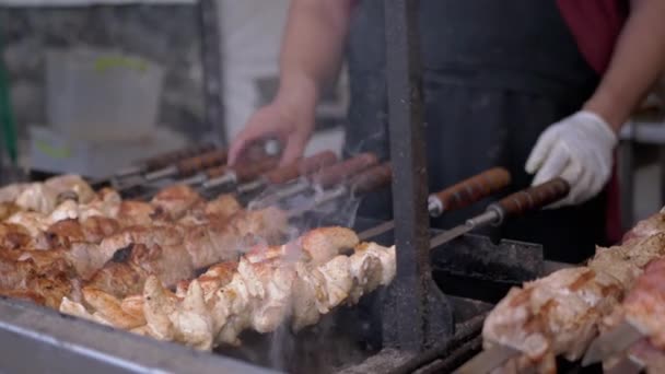 Cocinar Kebab de cerdo jugoso en una parrilla abierta en un patio de comidas en una brocheta de metal. Zoom: — Vídeo de stock