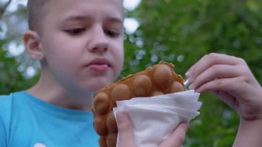 Çocuk Bench 'te oturur, Waffle kupasında kremalı dondurma yer, caddedeki parkta.