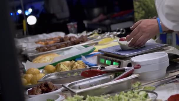 Продавец уличной еды взвешивает салат, кебабы в коробке для обедов по электронной шкале — стоковое видео